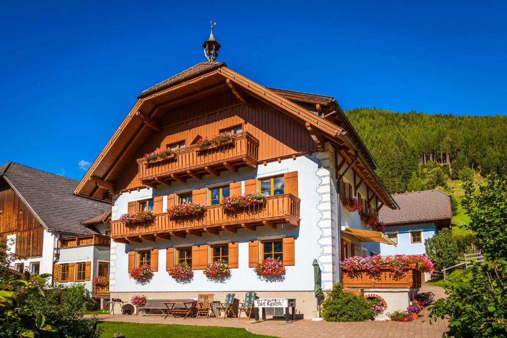 um edifício com um telhado de gambrel com caixas de flores em Hansalagut em Mauterndorf