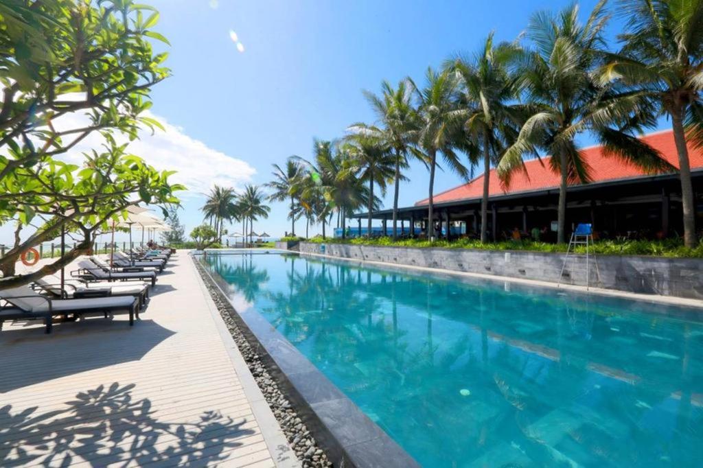 a swimming pool at a resort with palm trees at Sunshine Apartment in 5* resort in Da Nang