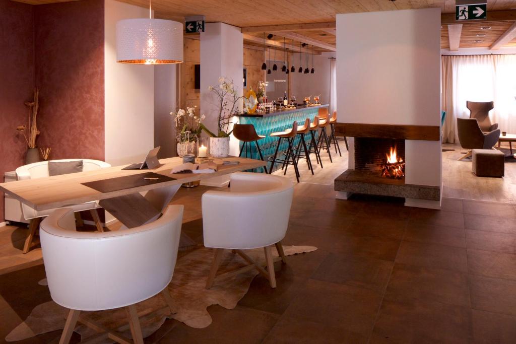 uma sala de jantar com lareira, mesa e cadeiras em Adults Only Hotel Mulin - Das Erwachsenen-Hotel in den Bergen em Brigels