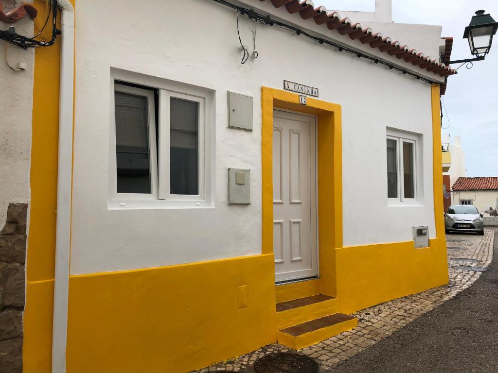 un edificio blanco y amarillo con puerta en Casinha Teles en Alvor