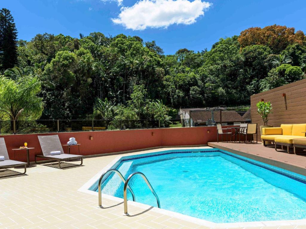 a swimming pool with two lounge chairs and a table at Mercure Joinville Prinz in Joinville