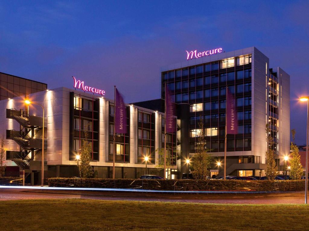 un bâtiment avec un panneau en haut de celui-ci la nuit dans l'établissement Mercure Hotel Groningen Martiniplaza, à Groningue