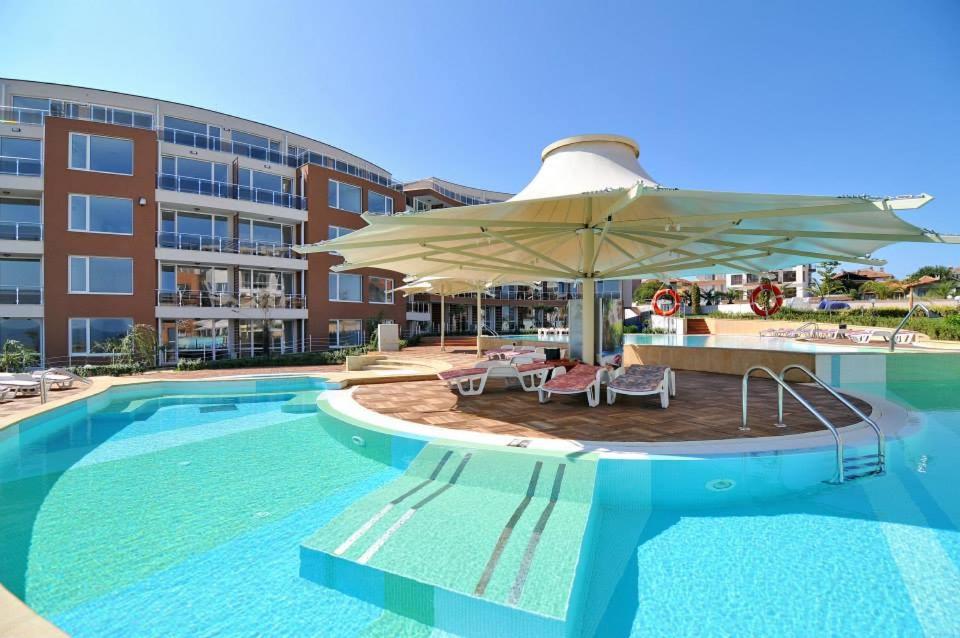 a pool with an umbrella and chairs and a hotel at Apartments Del Sol - Sunny Island Complex in Chernomorets