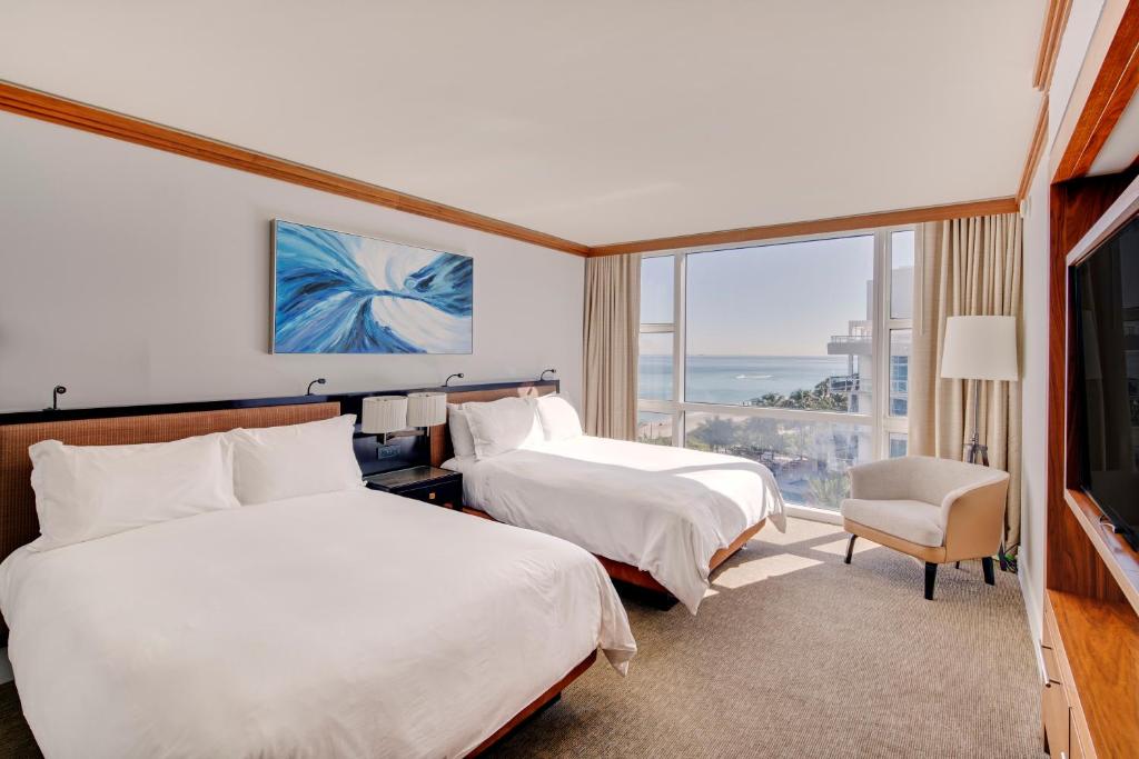 a hotel room with two beds and a large window at Carillon Miami Wellness Resort in Miami Beach