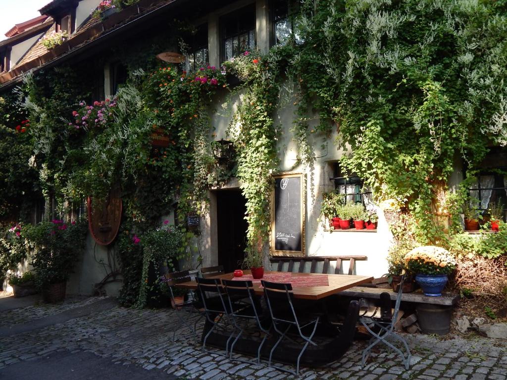 a table and chairs in front of a building with flowers at Altfraenkische Weinstube in Rothenburg ob der Tauber