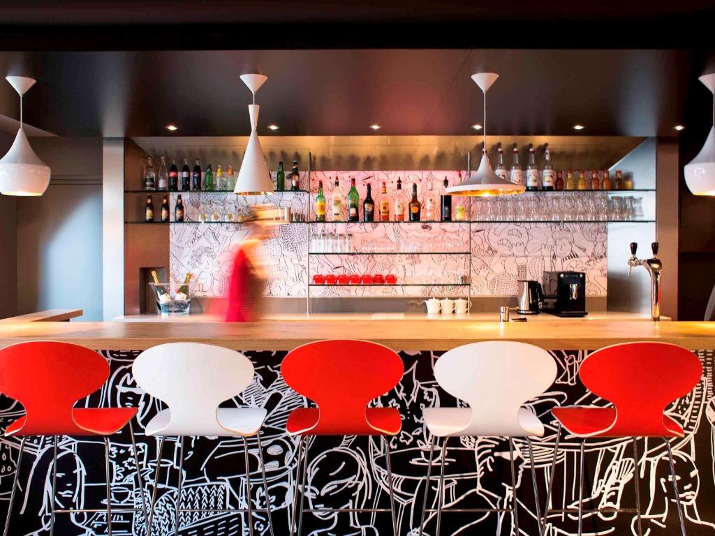a bar with red and white stools in a restaurant at ibis London Elstree Borehamwood in Borehamwood