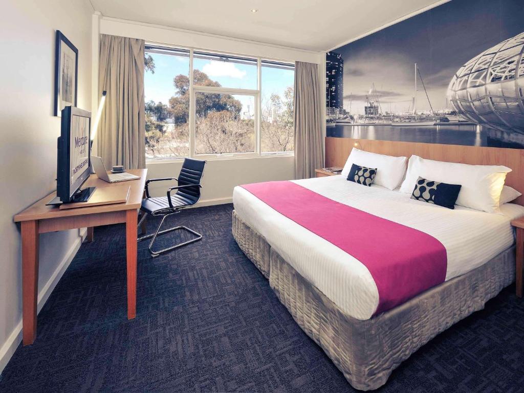 a hotel room with a bed and a desk and a television at Mercure North Melbourne in Melbourne