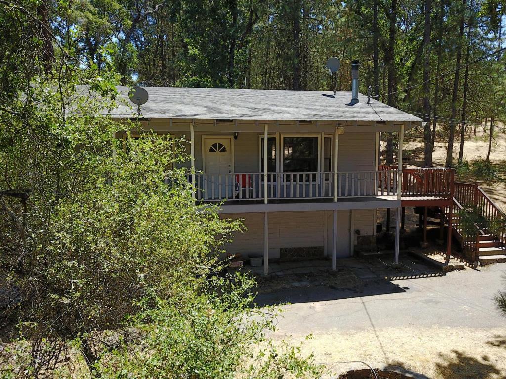 una pequeña casa amarilla con porche y terraza en Yosemite is Calling en Groveland