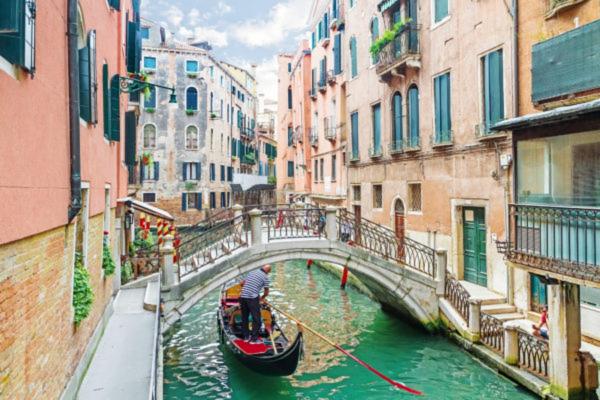 een man in een gondel in een kanaal met een brug bij Casa Marco Polo in Venetië