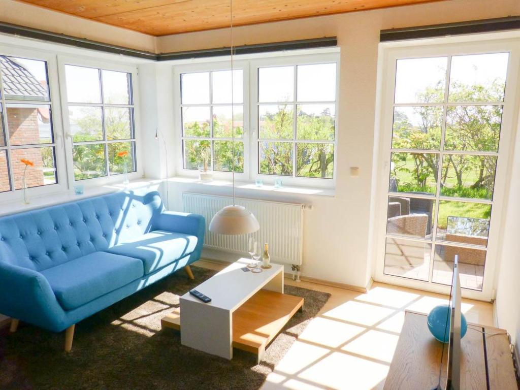 a living room with a blue couch and windows at Haus Nordlicht Ferienwohnung *At Nuurdlacht* in Nebel