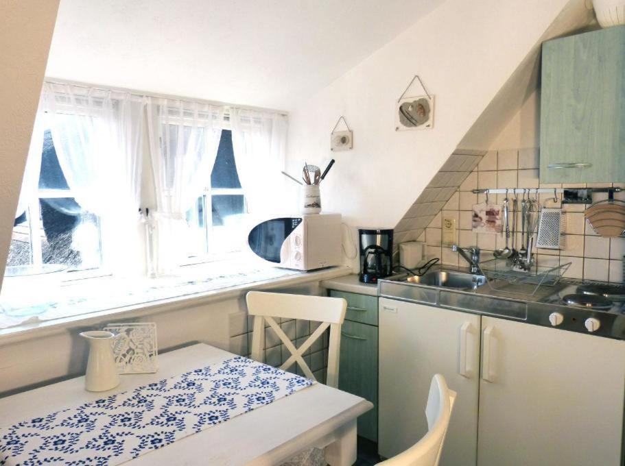 a kitchen with a table and a sink and some windows at Hüs Sanskiin Ferienwohnung *Eerdglüper* in Süddorf