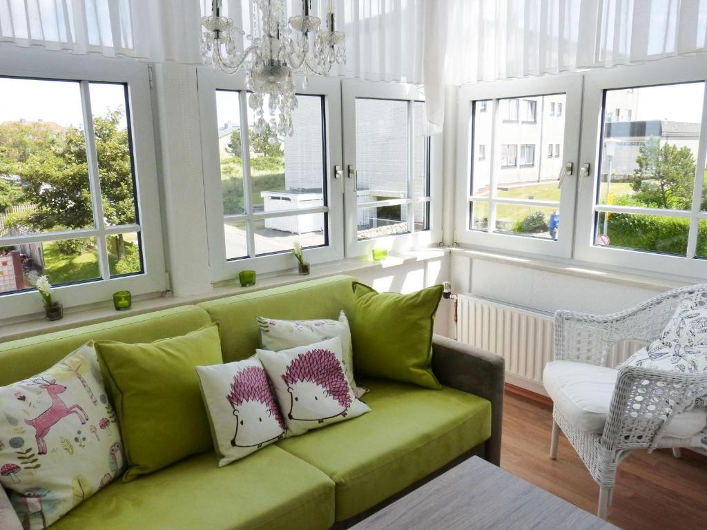 a green couch in a living room with windows at Haus Therese *FeWo 7* in Wittdün