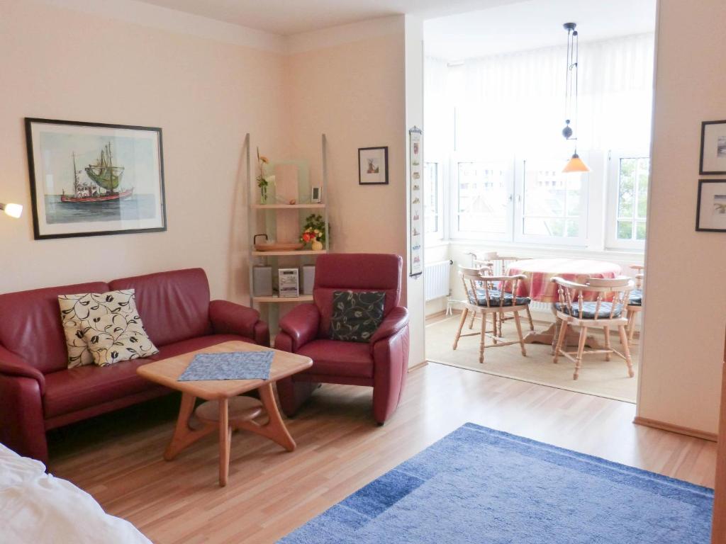ein Wohnzimmer mit einem roten Sofa und einem Tisch in der Unterkunft Haus Therese *FeWo 6* in Wittdün
