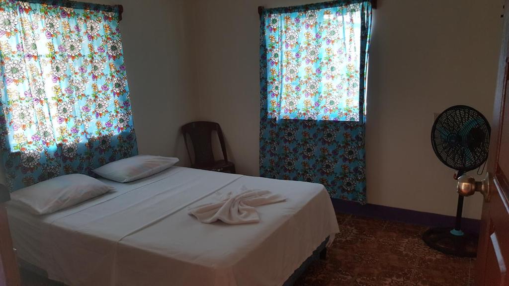 a bedroom with a bed with two windows and a fan at Sea View in Little Corn Island