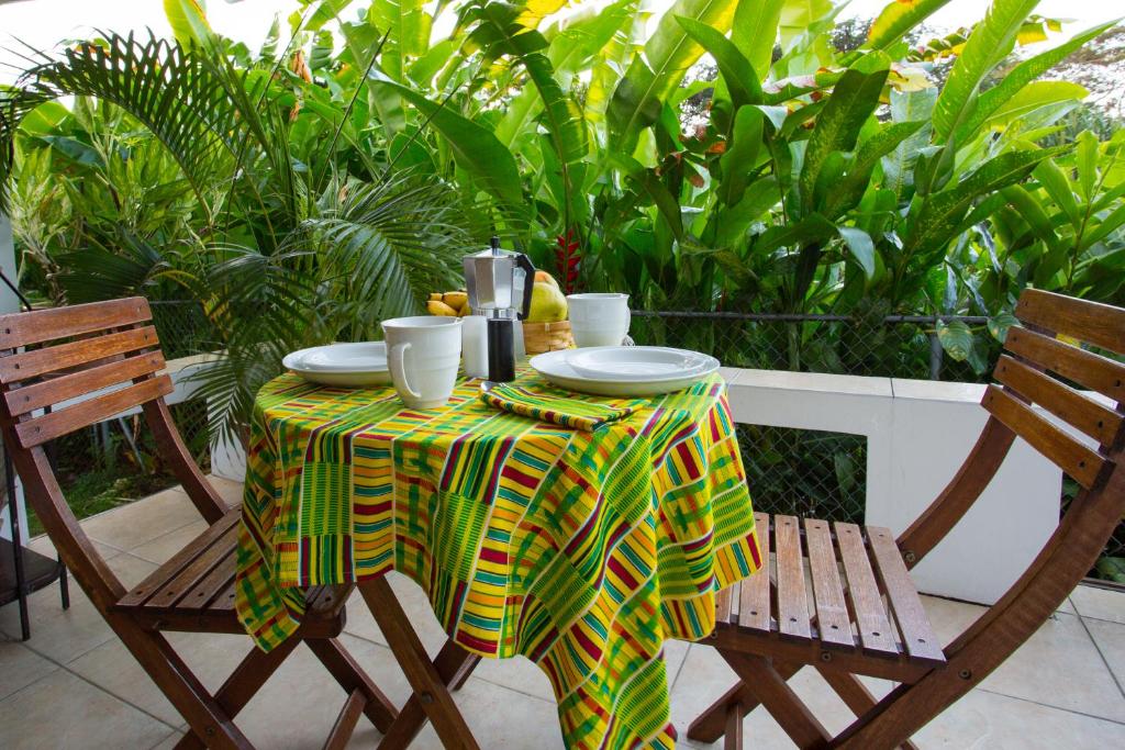 una mesa con un mantel verde y amarillo y dos sillas en smithy's eco-apartment en Morne Jaloux Ridge