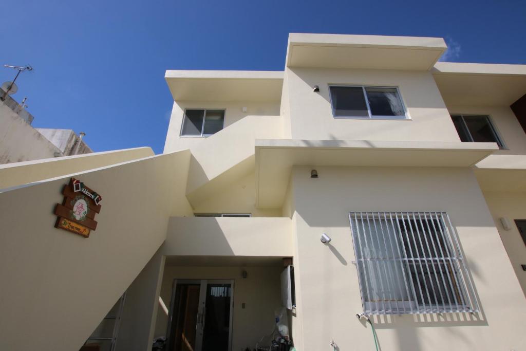 a white building with a blue sky in the background at Guesthouse Yu in Yomitan