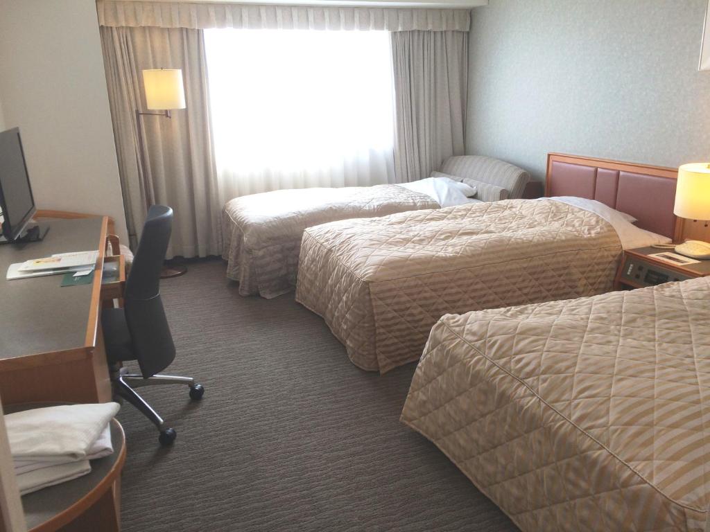a hotel room with two beds and a desk at Hotel Precede Koriyama in Koriyama