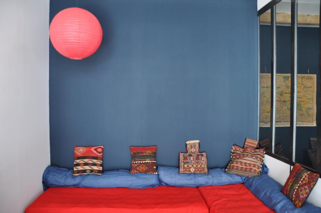 Sofá rojo con almohadas en una pared azul en Rouge Pompon, en Mèze