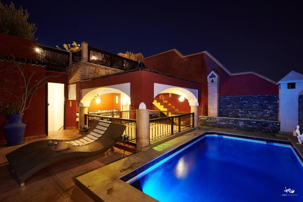 a swimming pool in front of a house at night at Riad Jenaï L'Authentique in Marrakesh