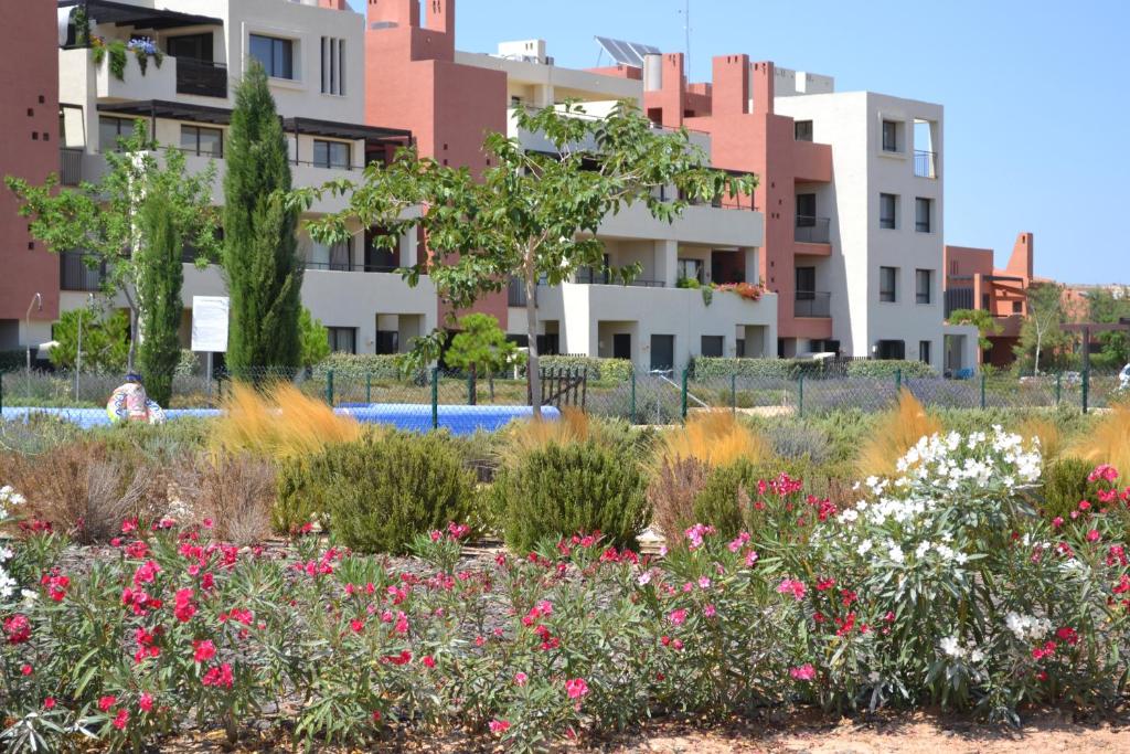 einen Garten mit Blumen vor den Gebäuden in der Unterkunft Corvera Golf and Country Club in Corvera