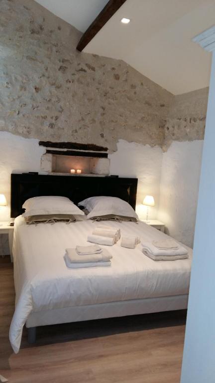 a bedroom with a large white bed with towels on it at Les chambres de la grange in Cherval