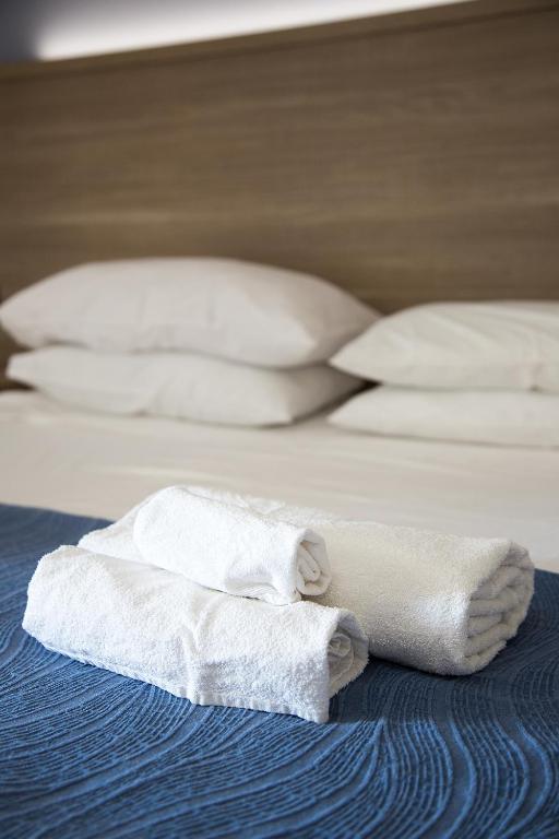two white towels sitting on a bed with pillows at Petruso Resort in Balestrate