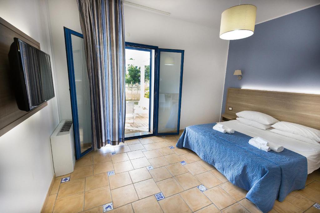 a bedroom with a bed with blue sheets and a television at Petruso Resort in Balestrate
