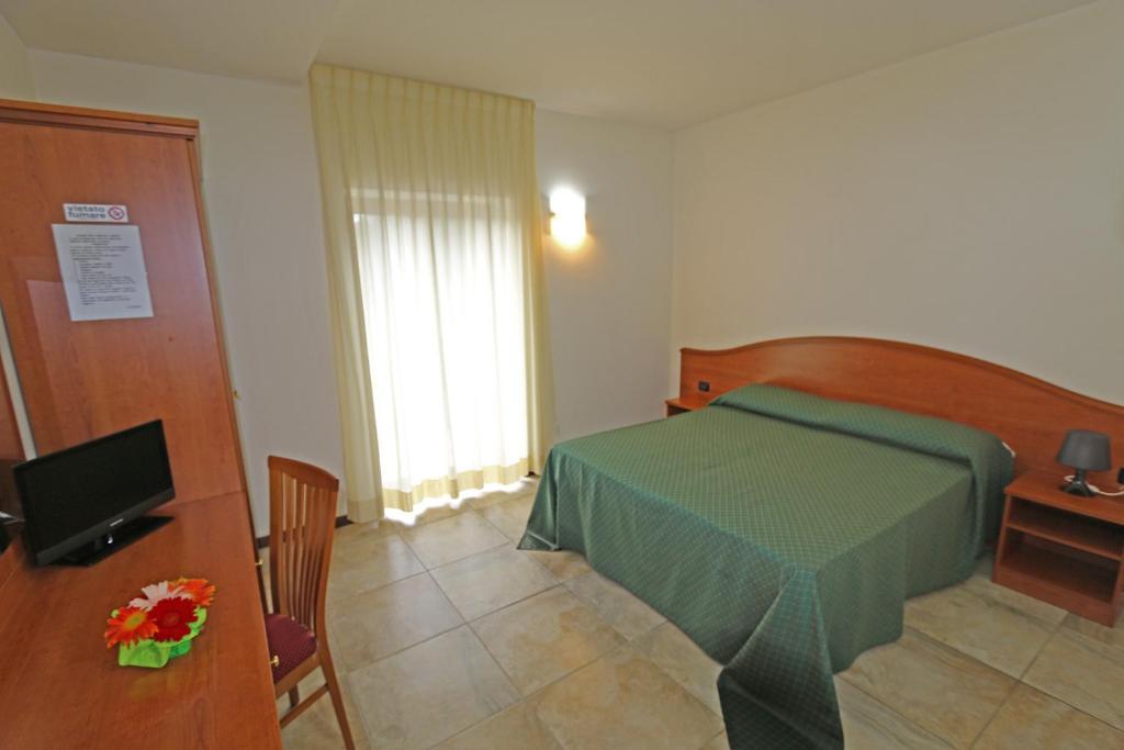 a bedroom with a bed and a desk and a television at Agriturismo Fasano in Cassano delle Murge