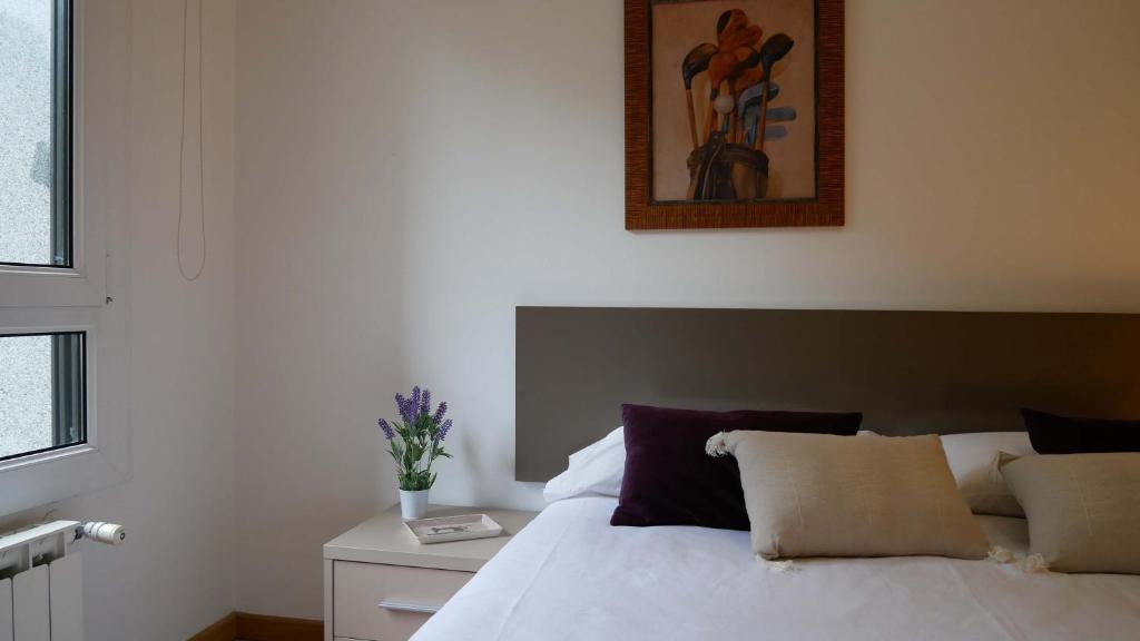 Un dormitorio con una cama blanca y una pintura en la pared en Apartamentos Antares 1, en Milladoiro