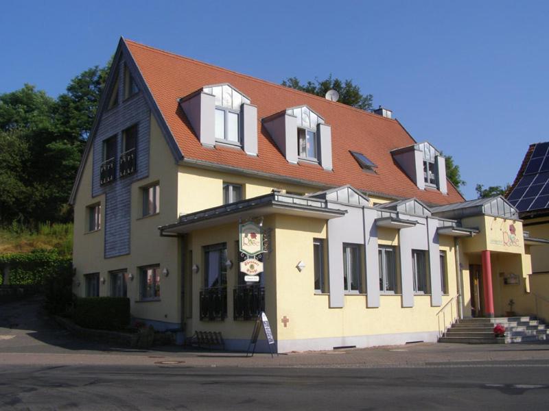 un grand bâtiment jaune et blanc avec un toit rouge dans l'établissement LandGASTHOF Rose, à Dammbach