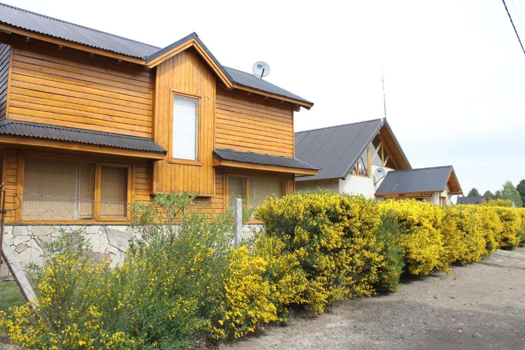 una casa con una fila de arbustos delante de ella en Complejo hotelero Illihue - Cabañas & Hostería en Junín de los Andes