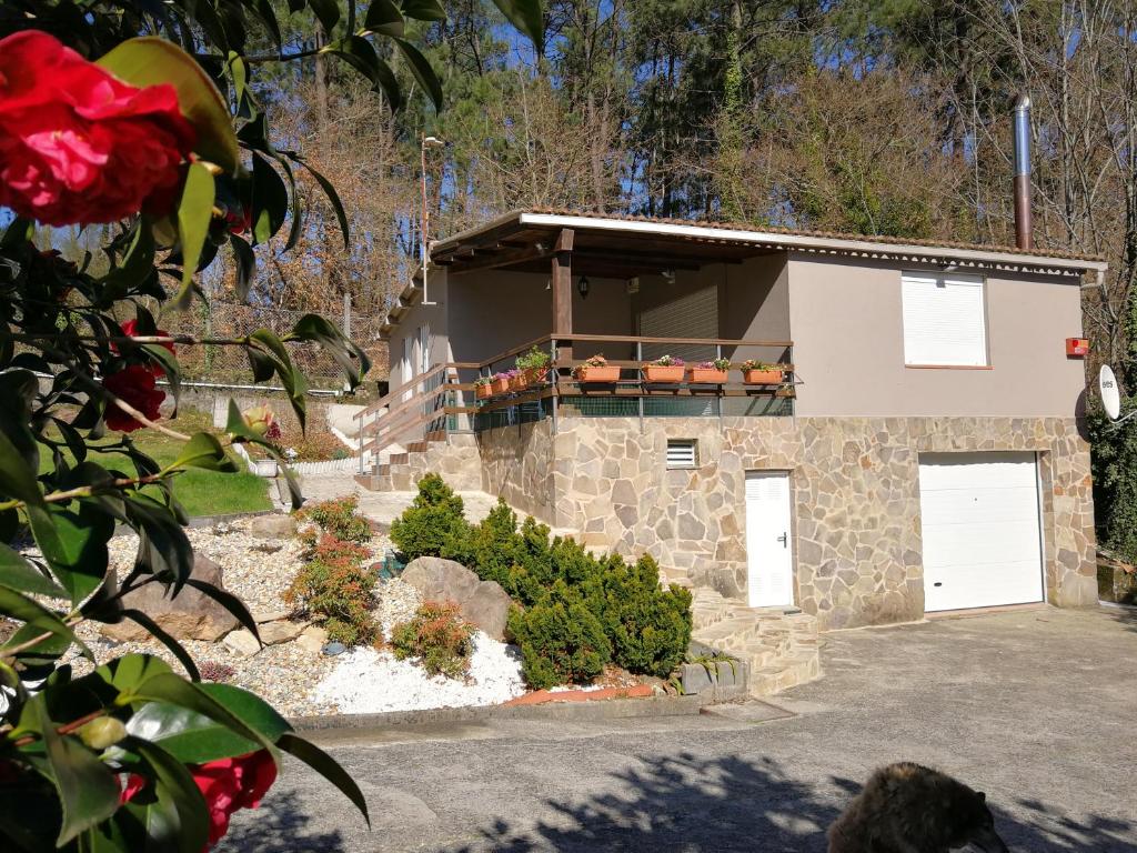 a building with two white garage doors and a red rose at casa Francelos in Rois