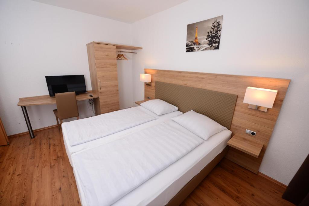 um quarto com uma cama e uma secretária com uma televisão em Hotel Linde Stuttgart em Stuttgart