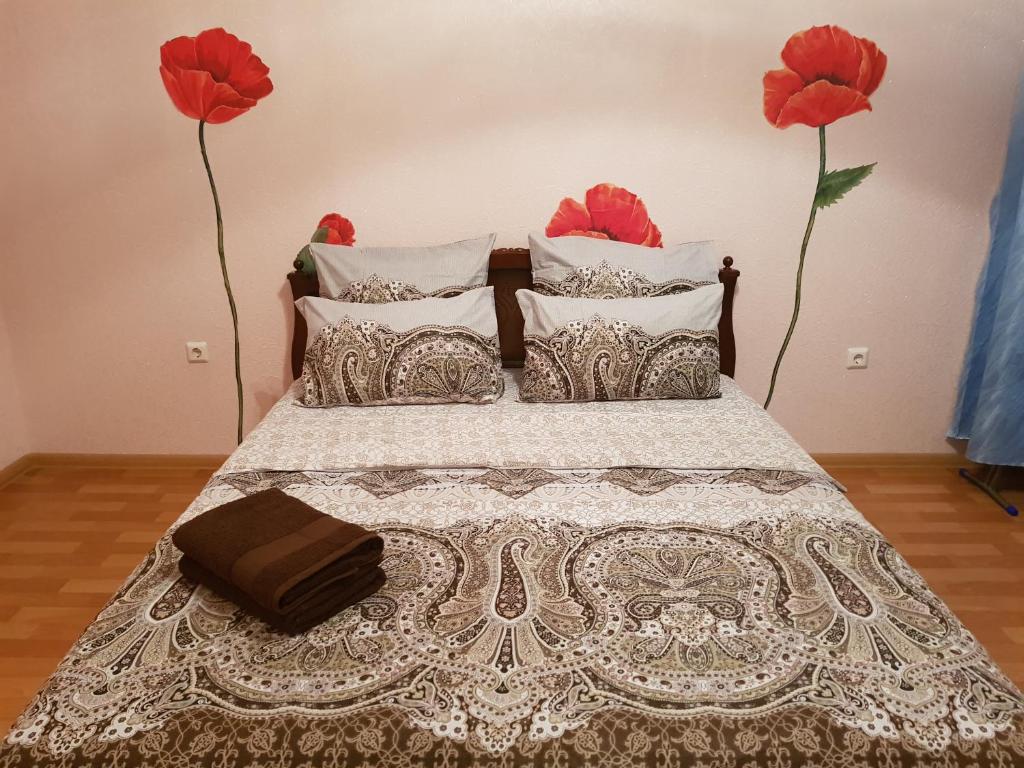 スタールイ・オスコルにあるДвухкомнатная кв на Степномの赤い花が2本の壁に飾られたベッド