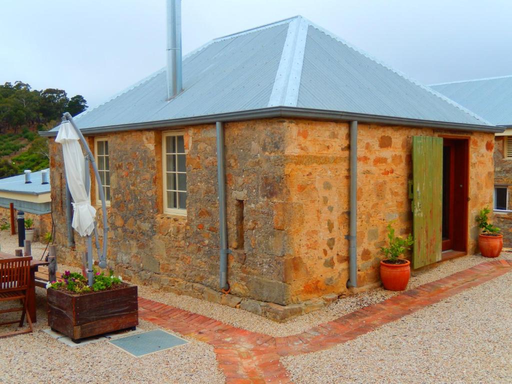 ein Steinhaus mit einem Dach und einer Terrasse in der Unterkunft Morialta Barns in Norton Summit