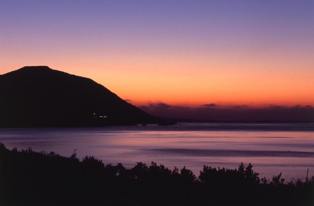 a sunset over the water with a mountain in the background at Anassa in Polis Chrysochous