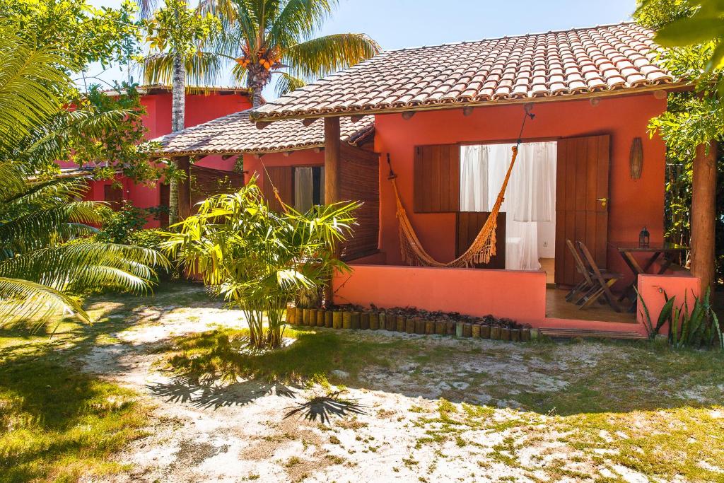 una casa roja con una hamaca delante en Pousada Do Guga, en Caraíva