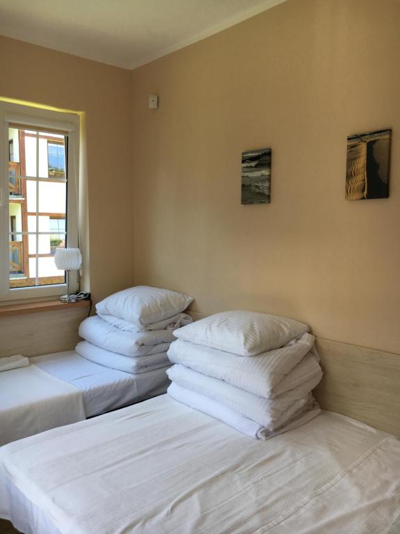 ロビにあるPlażowa 5の白い枕が備わる客室内のベッド2台