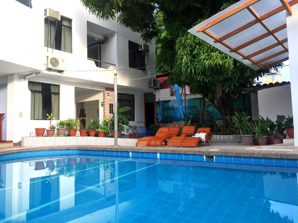a swimming pool with orange chairs and a building at Hotel Cielo Tarapoto in Tarapoto