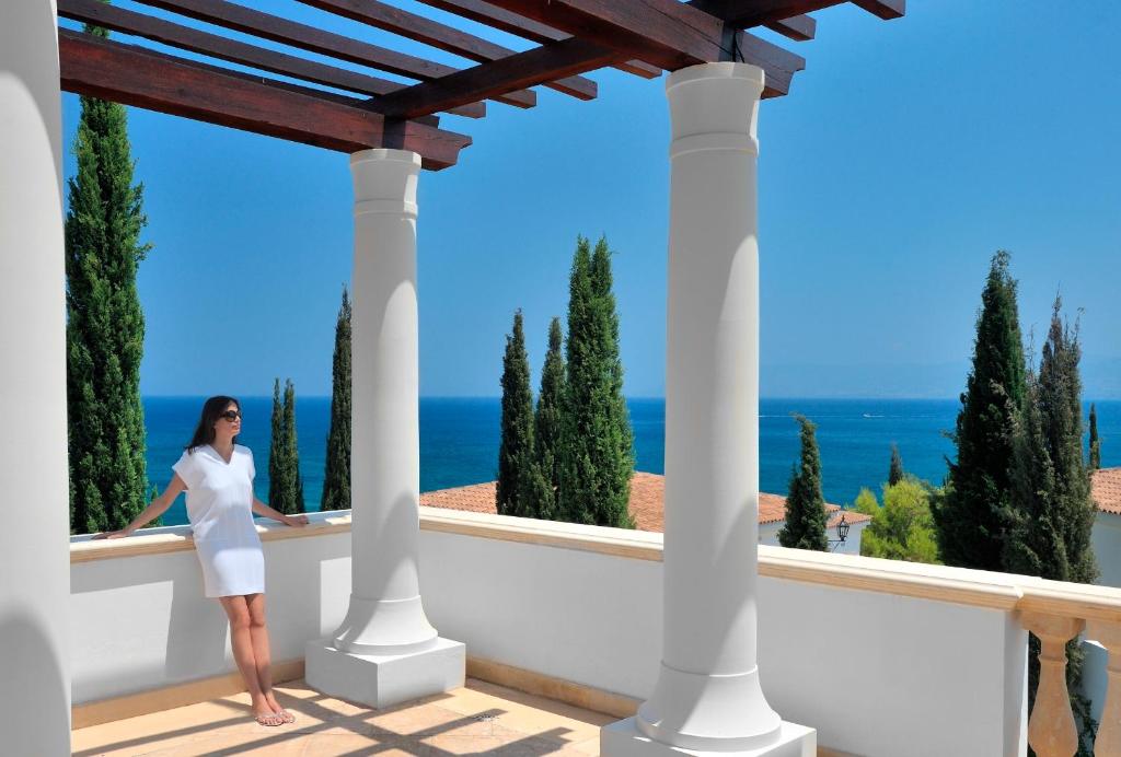 a woman standing on a balcony looking out at the ocean at Anassa in Polis Chrysochous