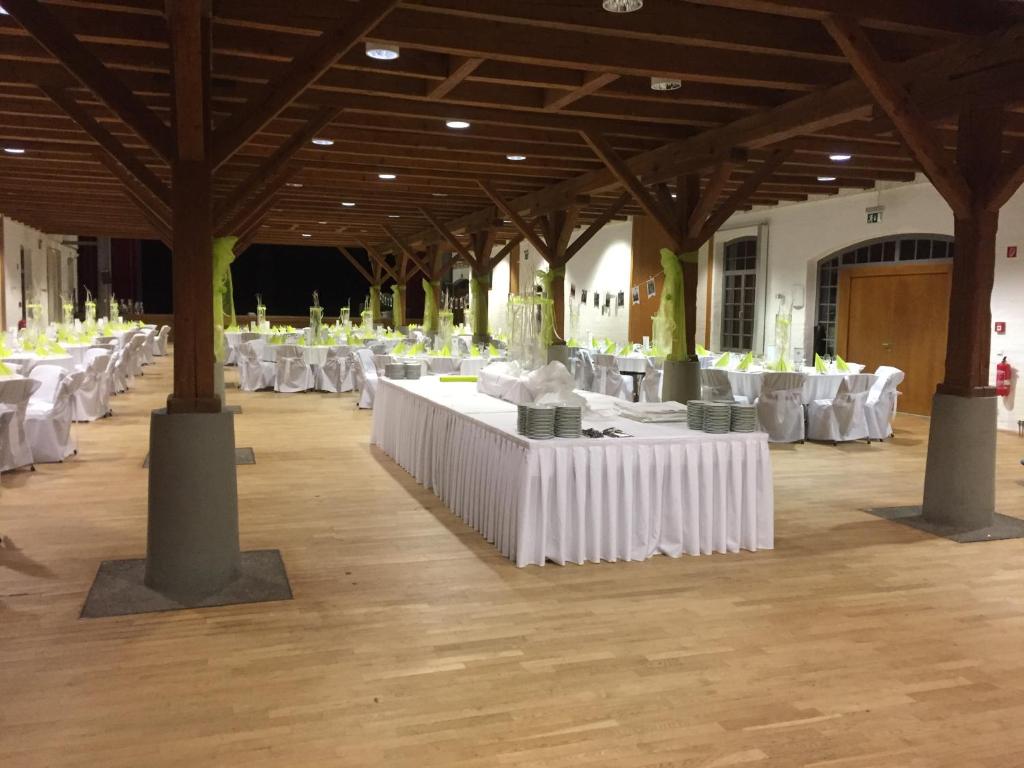 un gran salón con mesas y sillas blancas en deckert`s Hotel an der Klosterpforte, en Eisleben