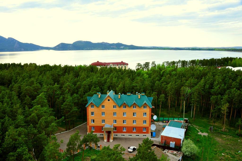 an orange building with a blue roof in front of a lake at Hotel Nurlytau in Borovoye