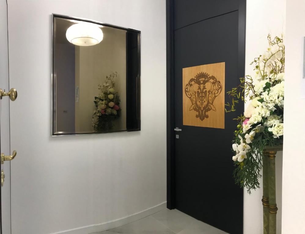サレルノにあるLuxury B&B Charlemagneの鏡と花の壁の黒い扉