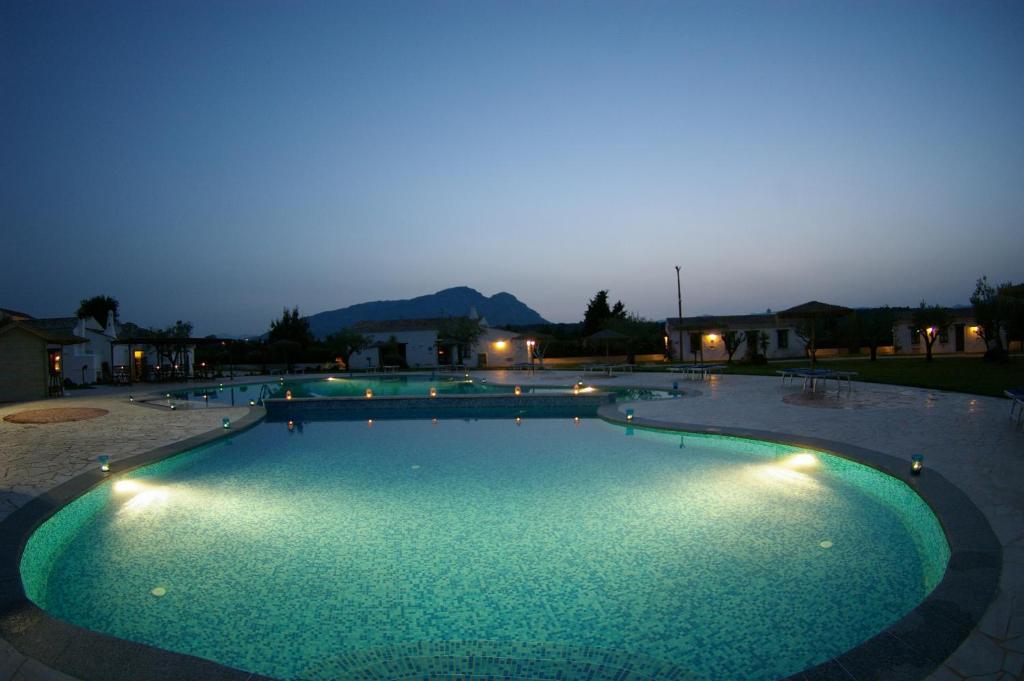 a large swimming pool at night with lights at Santa Maria Resort in Orosei