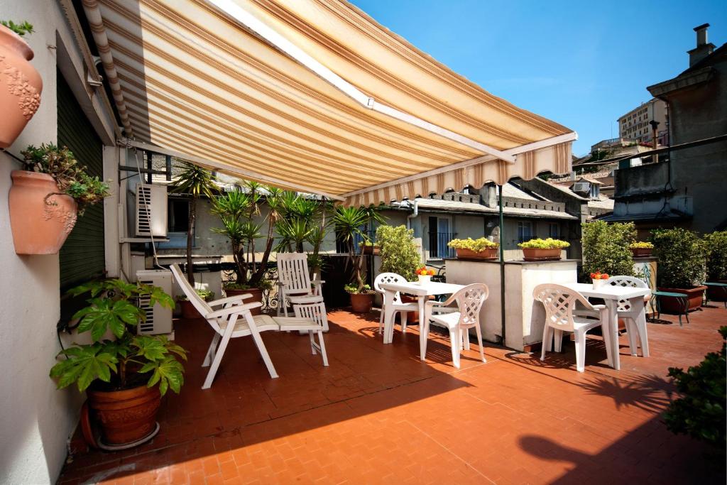 a patio with white chairs and tables and awnings at Hotel Cairoli in Genoa