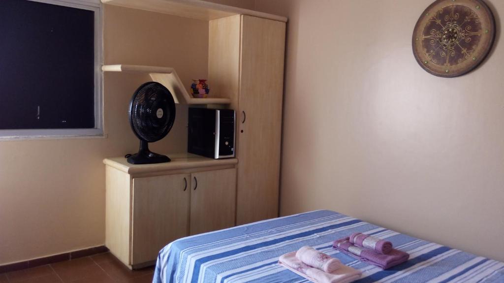 a bedroom with a bed with a microwave and a tv at Ap Acolhedor in Fortaleza