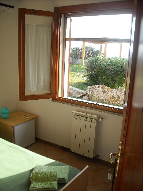 a bedroom with a window with a view of a yard at Agriturismo Depalmas in Stintino