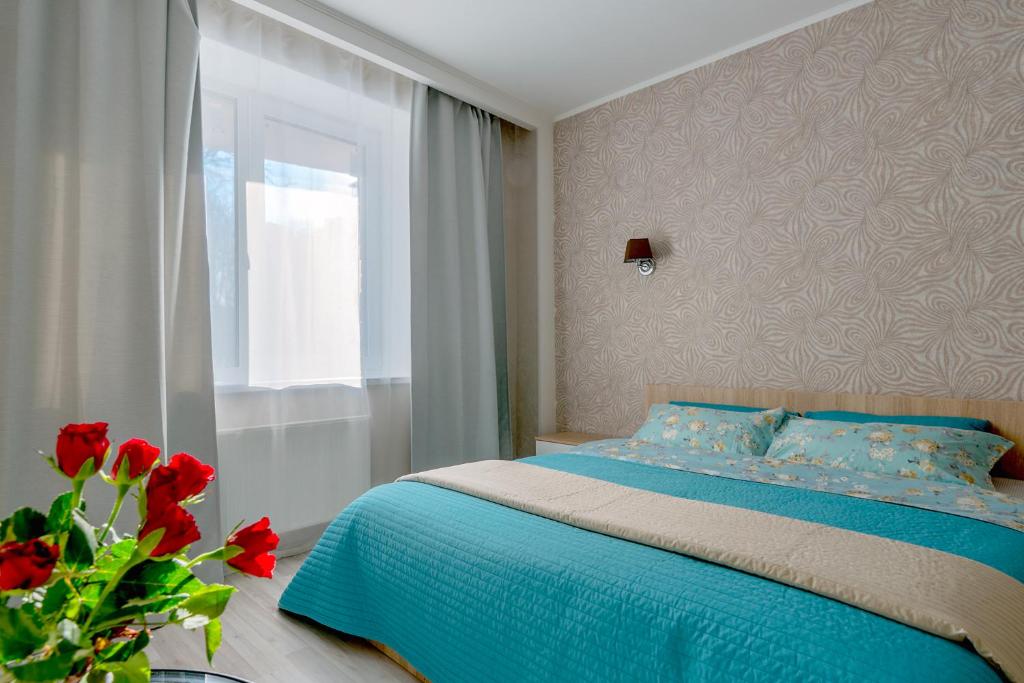 een slaapkamer met een bed met blauwe lakens en een raam bij Apartments at Yaroslavskiy prospekt in Sint-Petersburg