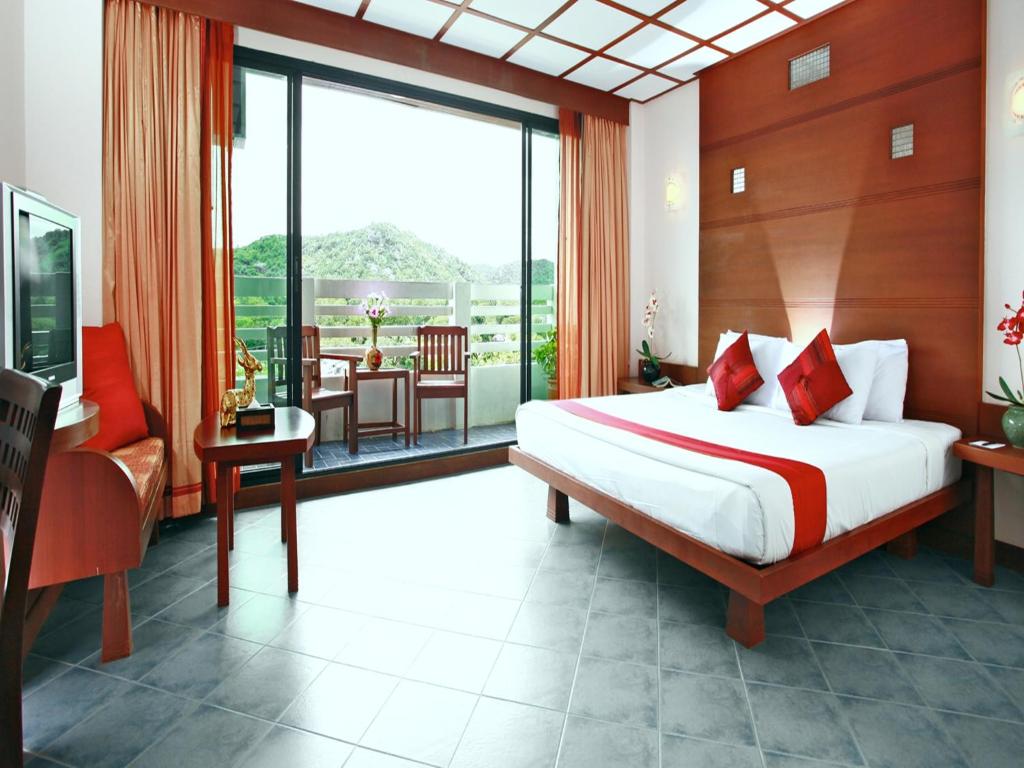 a bedroom with a bed and a balcony with a table at Hua Hin Loft in Hua Hin