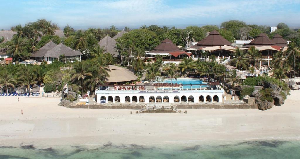 
a beach scene with a house and a boat at Leopard Beach Resort and Spa in Diani Beach
